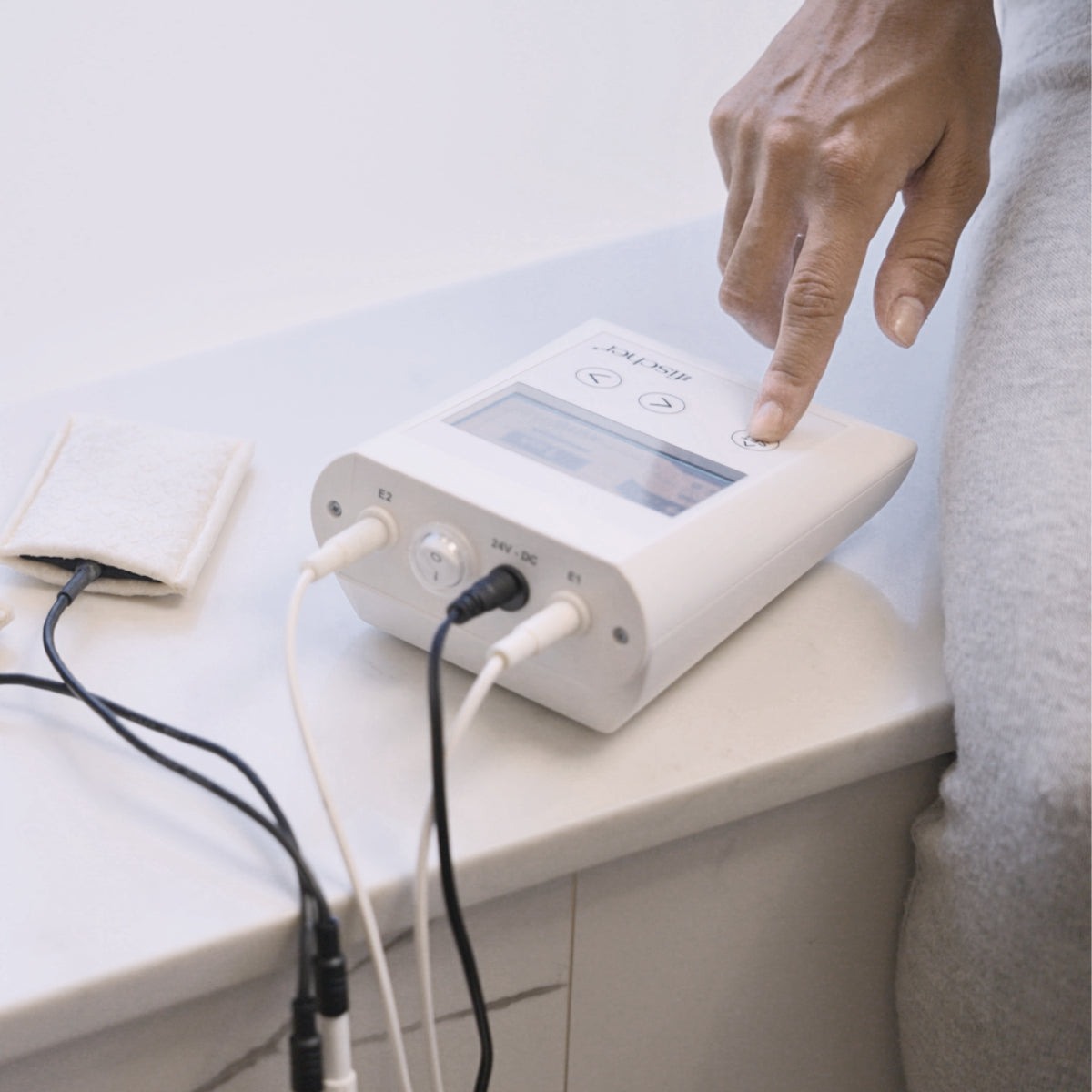 A person using the Fischer iontophoresis device, used to treat hyperhidrosis or excessive sweating with the underarm attachments next to it 